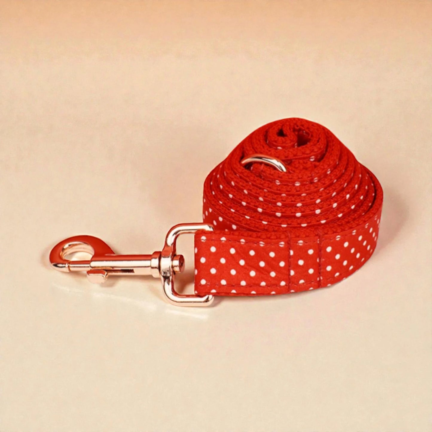 Red polka dot dog lead with a silver clip on a beige background