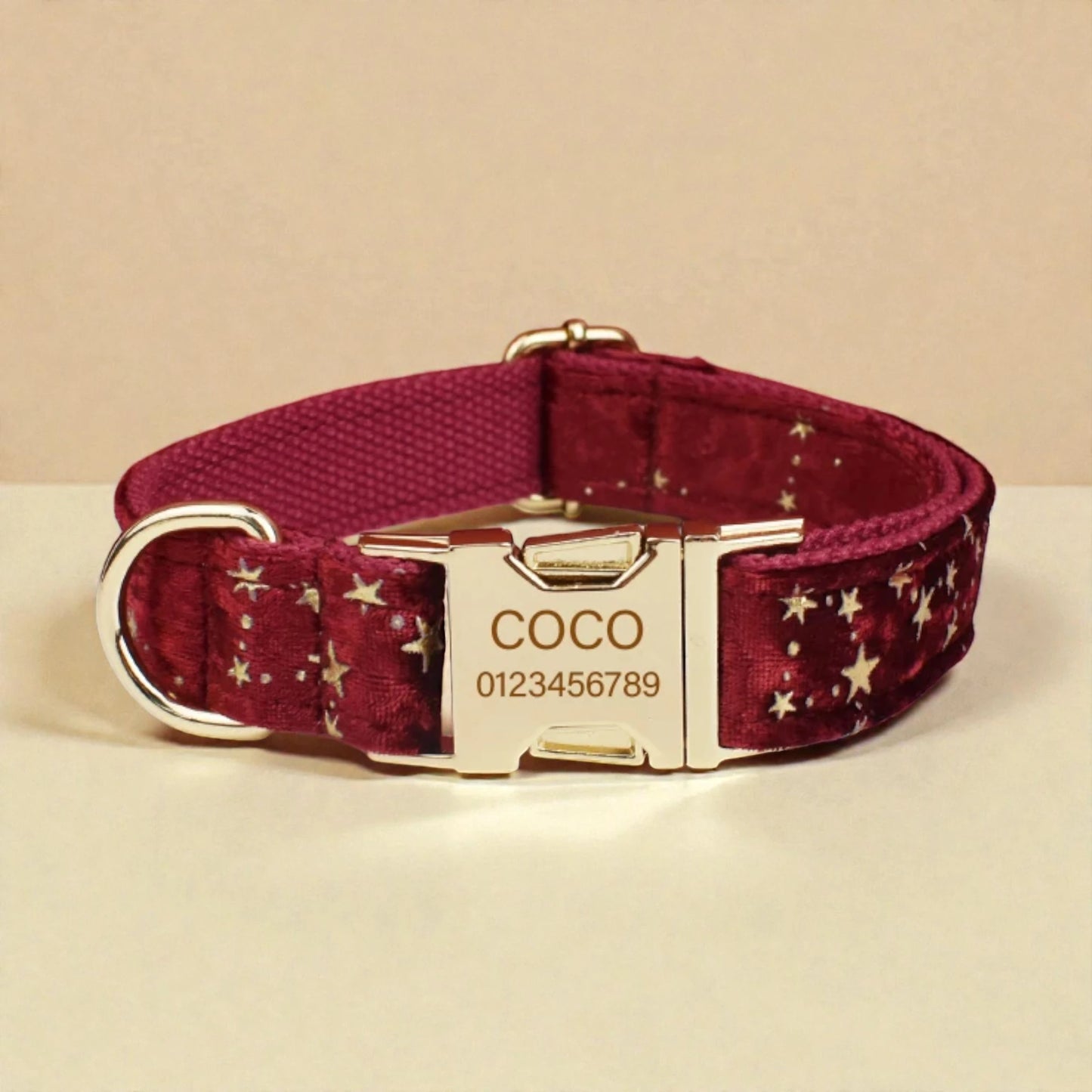 Red dog collar with star pattern and gold buckle on a beige background