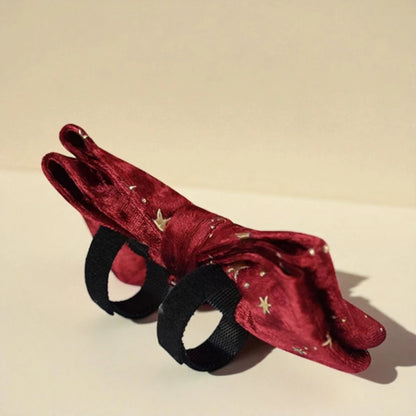 Red velvet headband with gold stars and black ribbons on a beige background