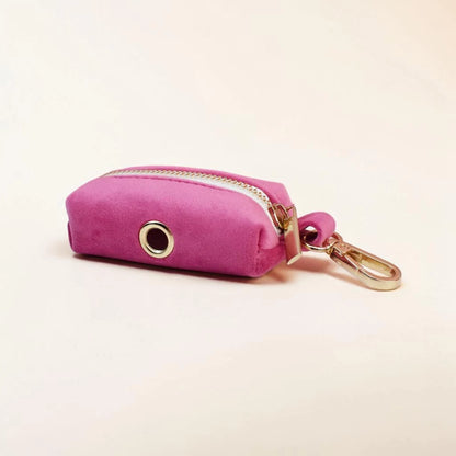 Pink dog poop bag holder with gold clip on a light pink background
