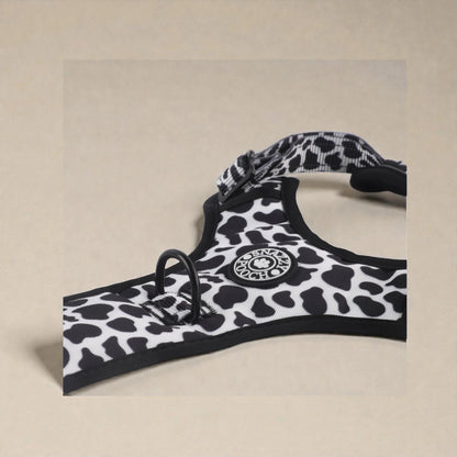 Black and white cow print patterned dog harness on a beige background
