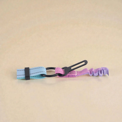 Pink and blue dog lead with seat belt attachment on a beige background