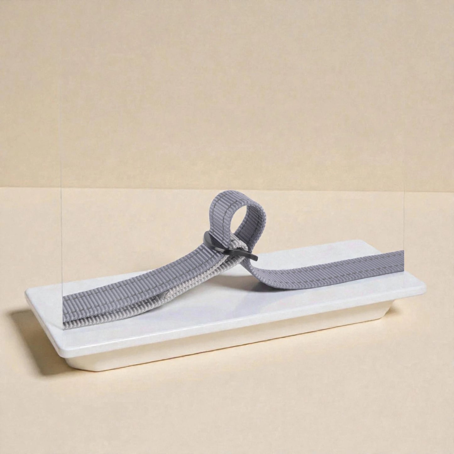 Grey and black dog lead adjuster on a beige background