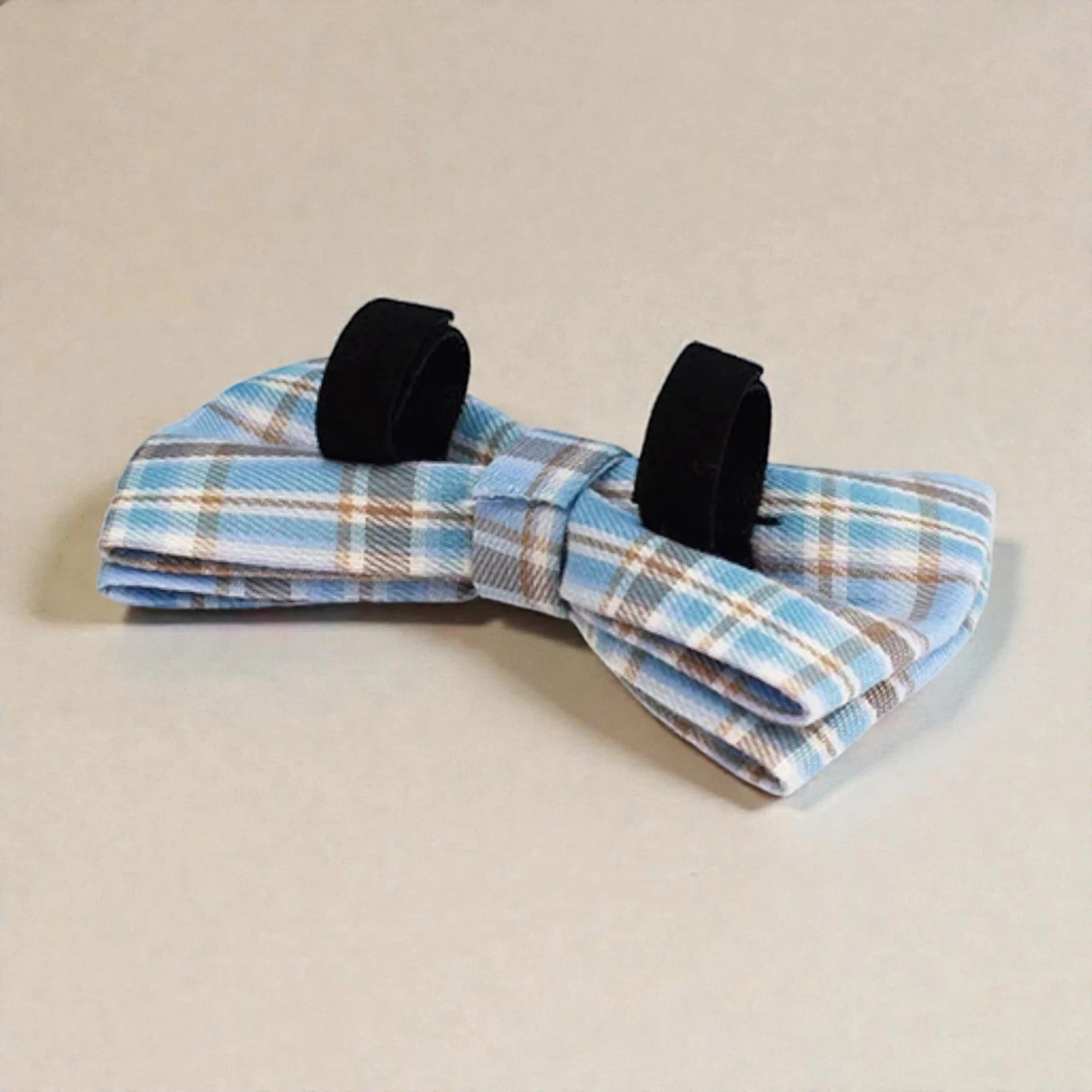 Blue plaid bow tie with black velvet accents on a beige background