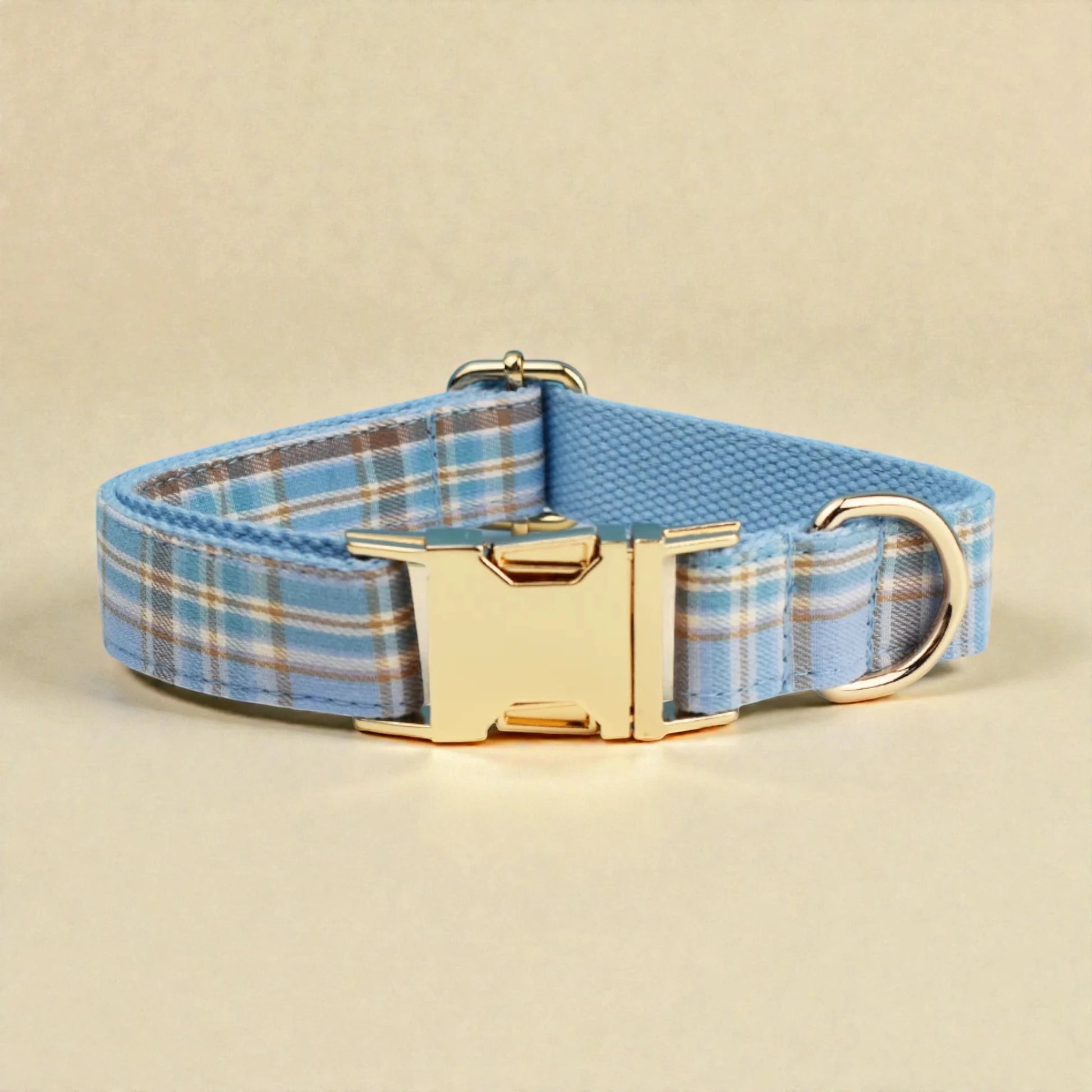 Dog collar with blue plaid pattern and gold buckle on beige background