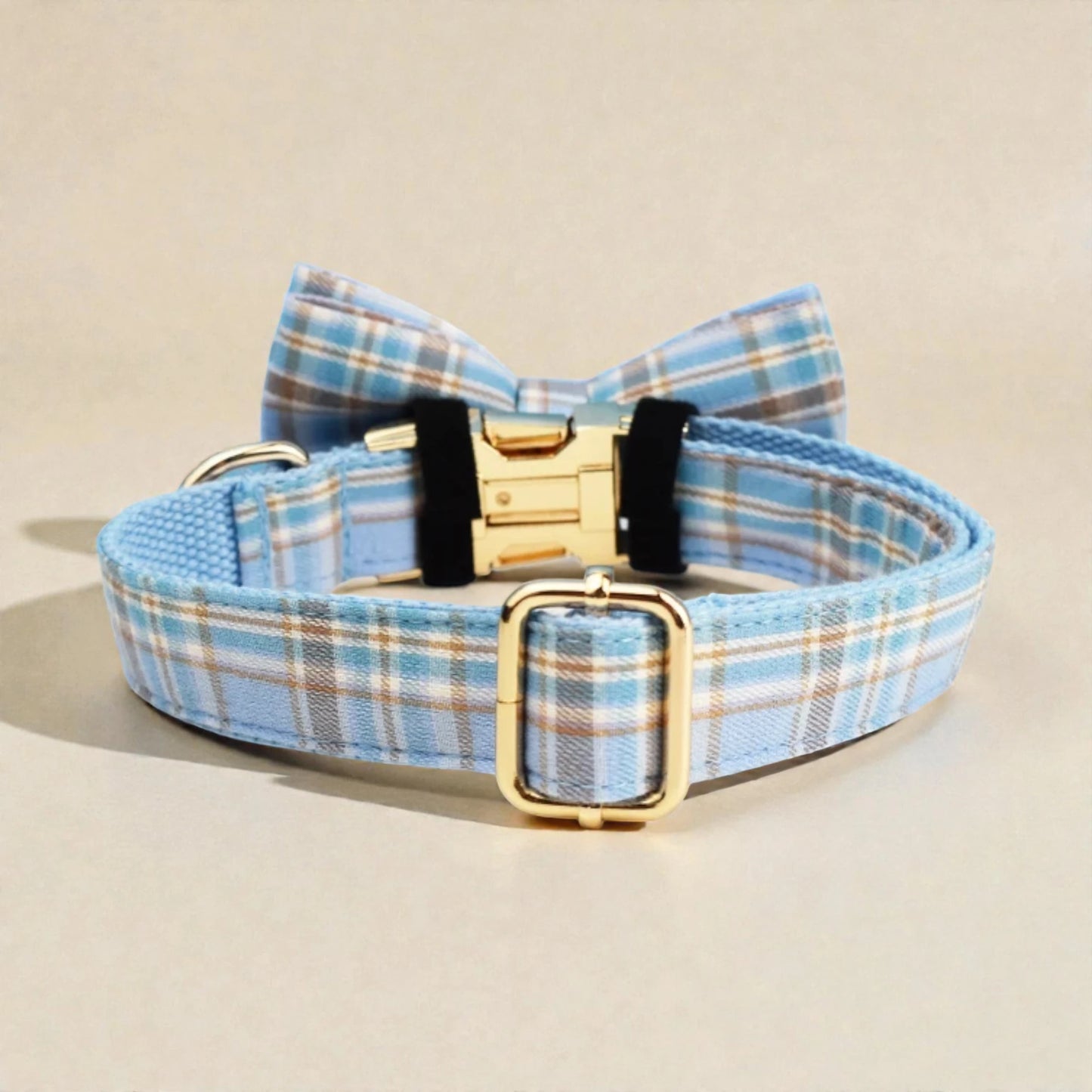 Blue plaid dog collar with a bow tie and gold buckle on a beige background