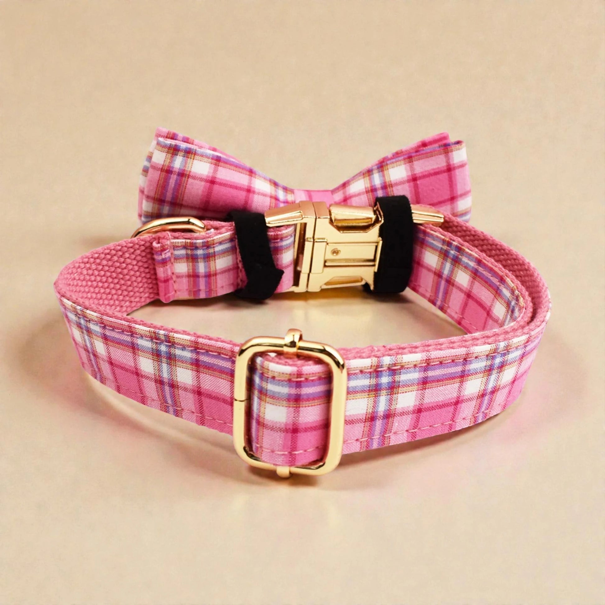 Pink plaid dog collar with a bow tie and gold buckle on a beige background