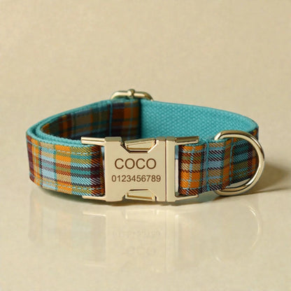 Plaid teal dog collar with a metallic buckle and engraved nameplate on a beige background