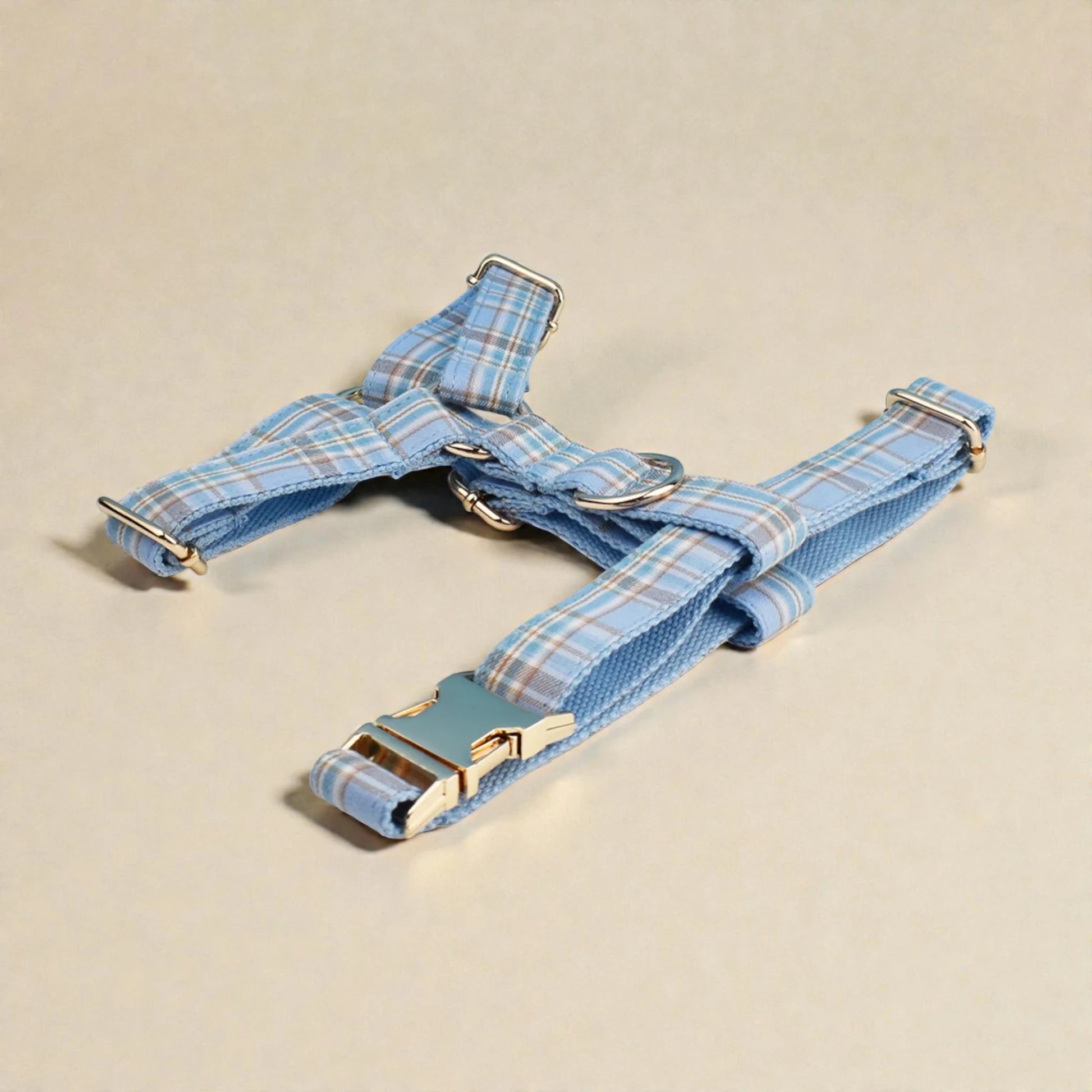 Blue plaid dog harness with gold hardware on a beige background