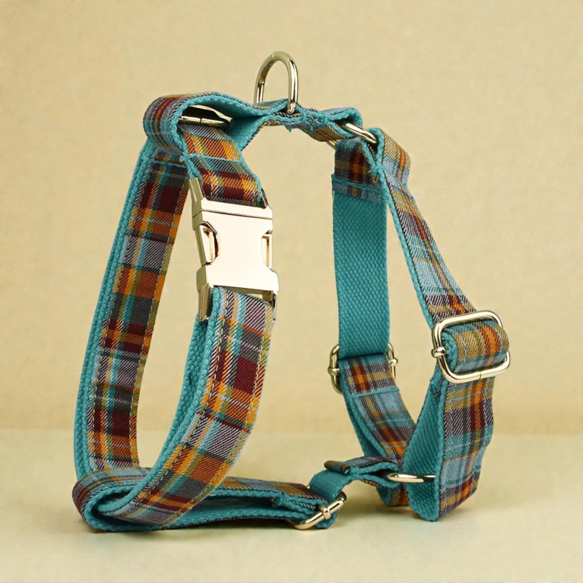 Plaid teal dog harness with teal accents on a beige background