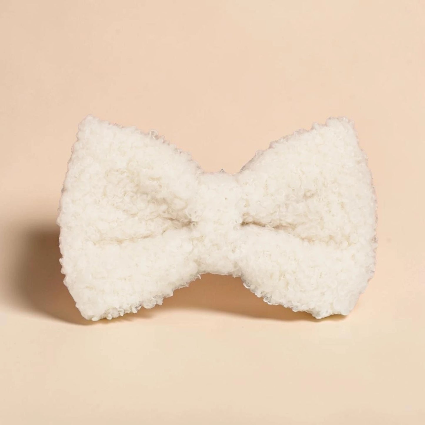 White teddy fleece dog bow on a beige background