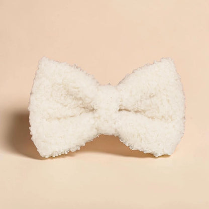 White teddy fleece dog bow on a beige background
