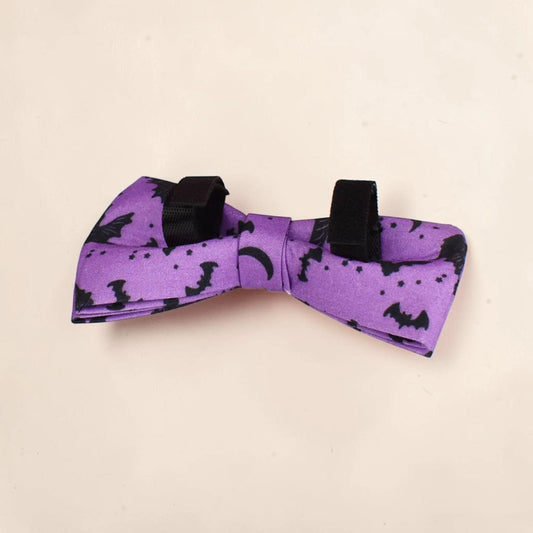 A purple detachable dog bow tie with a black print of bats, moons and stars. Perfect for Halloween.