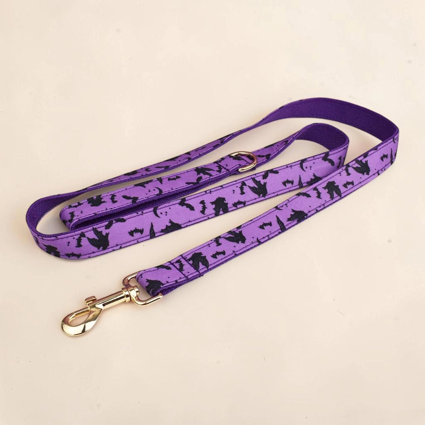 A purple dog lead with a black bat pattern, featuring a gold metal clasp.