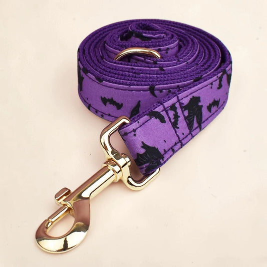 A purple dog lead with a black bat pattern, featuring a gold metal clasp.