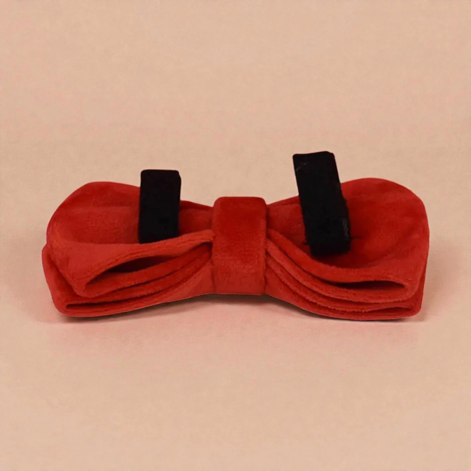 Red bow tie with black straps on a beige background