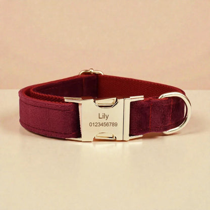Red wine dog collar with a metallic buckle and engraved nameplate on a beige background