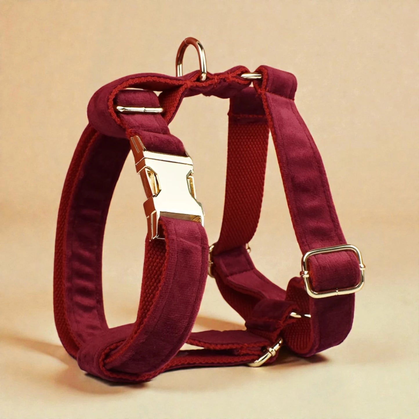 Red wine dog harness with gold hardware on a beige background