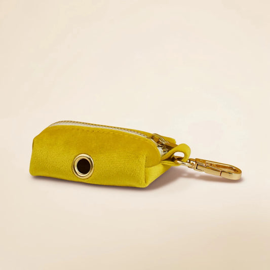 Yellow dog poop bag holder with a gold zip on a beige background