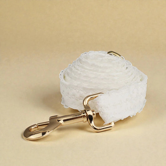 White lace dog lead with a gold clasp on a beige background