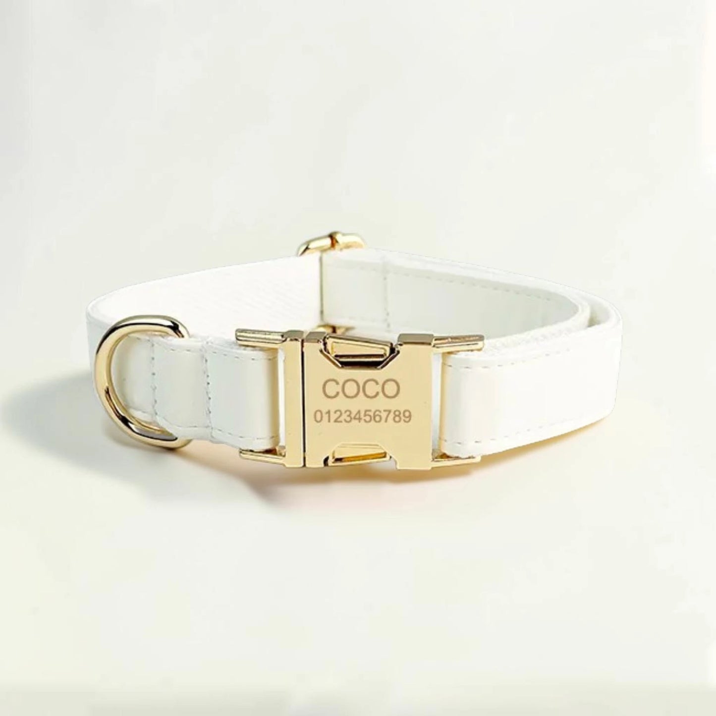 White dog collar with gold buckle and engraved details on a light background