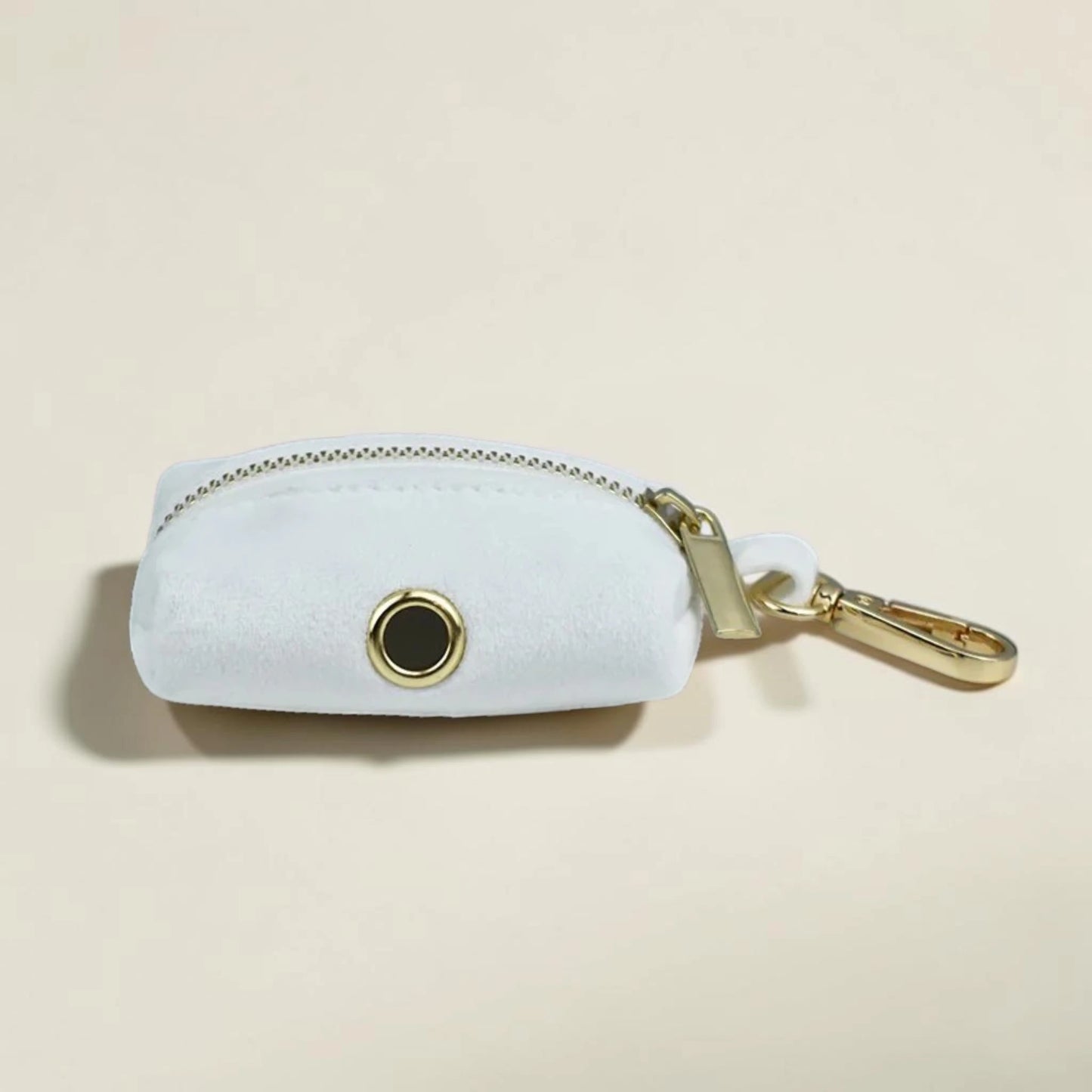 White dog poop bag holder with gold zip and clip on a beige background