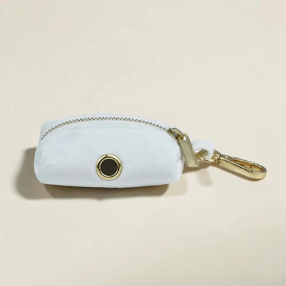 White dog poop bag holder with gold zip and clip on a beige background