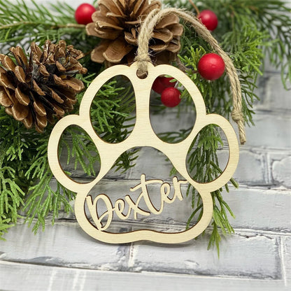 Wooden paw print ornament with 'Dexter' on a Christmas tree background