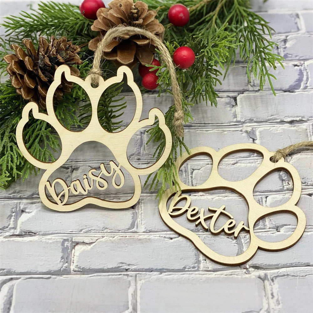 Two gold paw-shaped ornaments with names 'Daisy' and 'Bella' on a brick wall background.